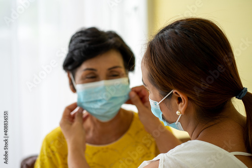 Asian sick old woman wearing protective face mask sitting with daughter helping