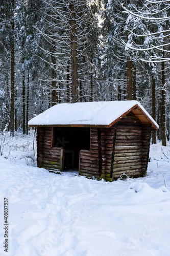 Small wooden shelter in snowy forest