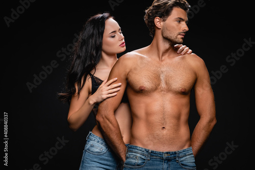 seductive brunette woman hugging muscular man looking away isolated on black