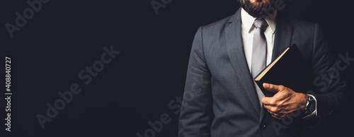 Photography man in suit holding a bible in his arm on a black background