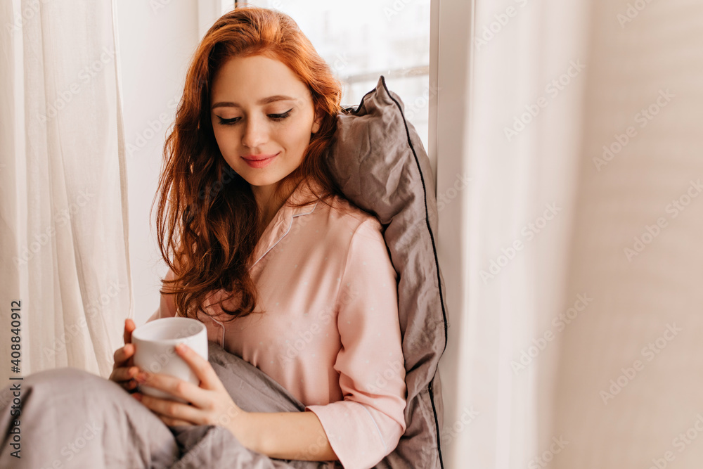 Relaxed girl in pajama drinking coffee. Indoor portrait of good-looking ginger woman enjoying tea. Relaxed girl in pajama drinking coffee. Indoor portrait of good-looking ginger woman enjoying tea.