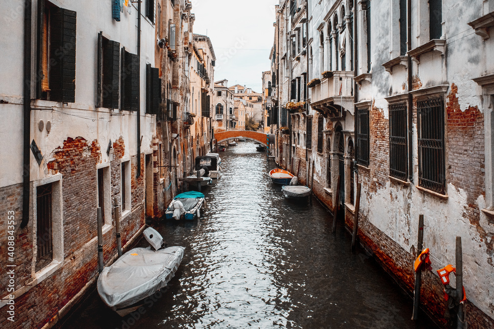 Canal with boats between old houses in Venice, Italy