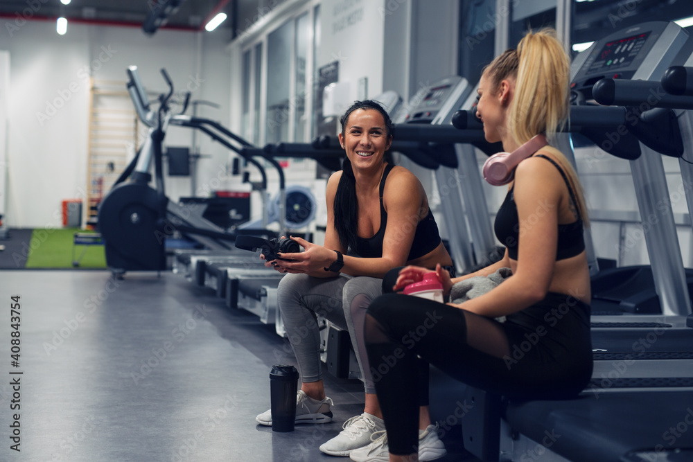 Fit young woman sitting and resting after workout or exercise in fitness gym Fit young woman sitting and resting after workout or exercise in fitness gym