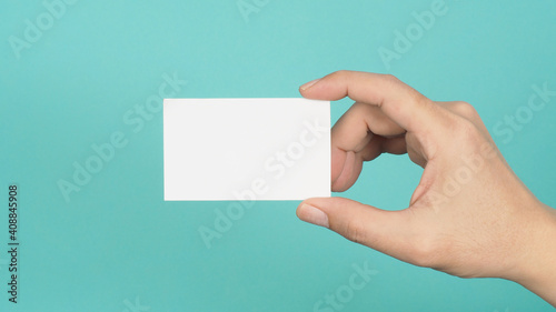 Male hand holding white blank card isolated on green or Tiffany Blue background.Empty space for text.