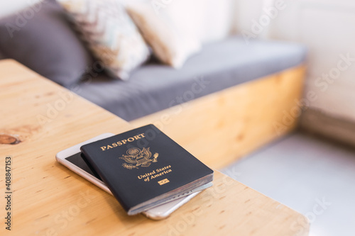 A blue American passport with a white smartphone sitting on top of a modern wooden table table