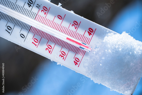 The thermometer lies on the snow in winter showing a negative temperature. Meteorological conditions in a harsh climate in winter with low air and ambient temperatures.Freeze in wintertime