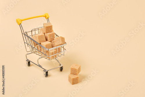 brown sugar cubes in a miniature shopping trolley on a beige background