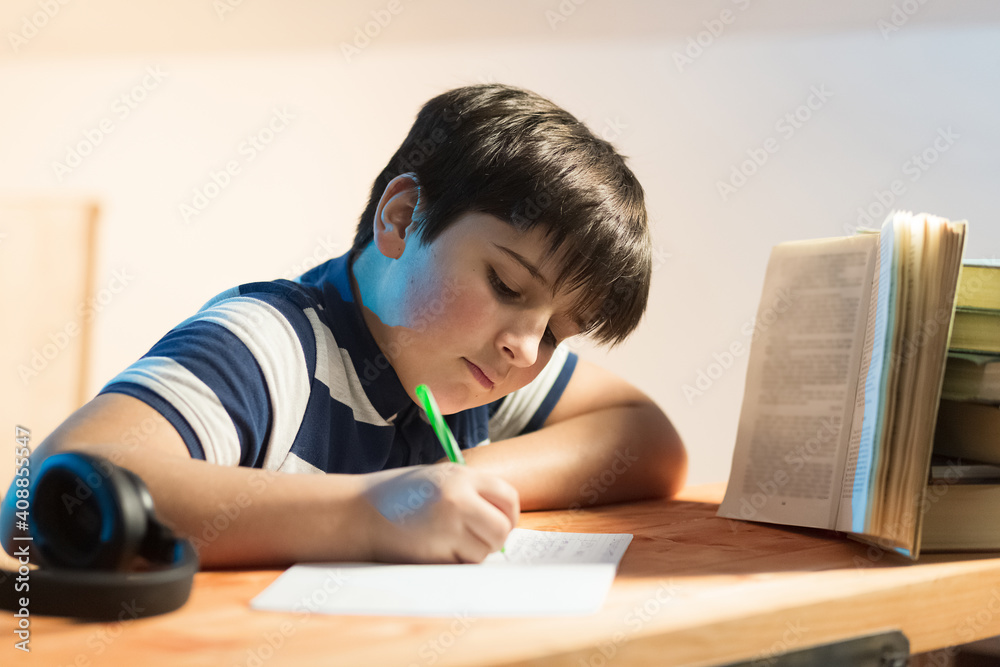 Calligraphy classes. boy in front of a book while busy rewriting text. Horizontal composition Calligraphy classes. boy in front of a book while busy rewriting text. Horizontal composition
