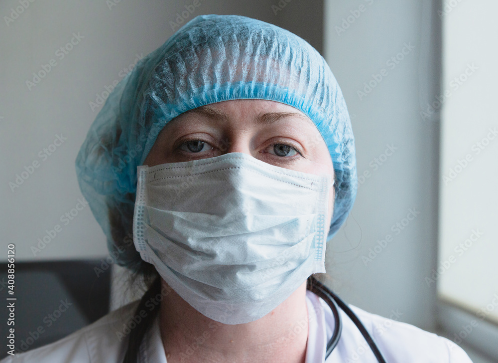 A portrait of a female doctor. Medical equipment protective medical mask cap and white coat. A portrait of a female doctor. Medical equipment protective medical mask cap and white coat.