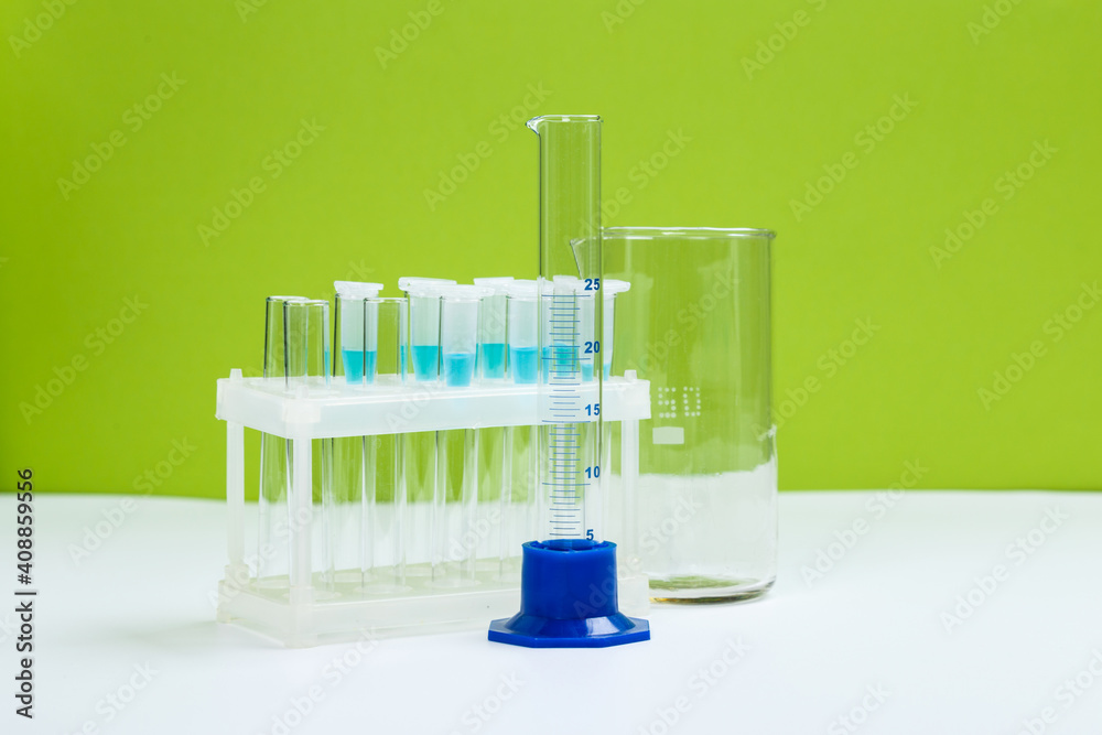 Various laboratory glass items with water and empty on white table with green background