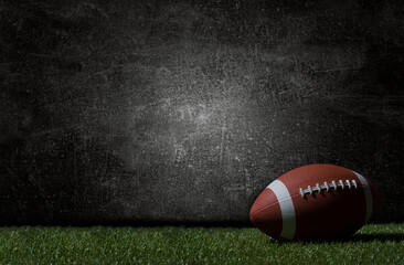 American football on green grass, on dark background. Team sport concept