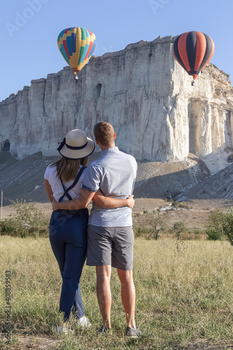 A young couple hugged or admired the balloons against the background of the White Rock on a Warm Summer day.