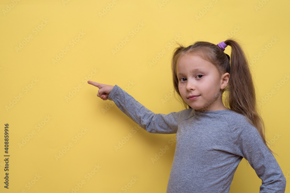 A cute girl in a gray T-shirt shows emotions on a yellow background. A cute girl in a gray T-shirt shows emotions on a yellow background.