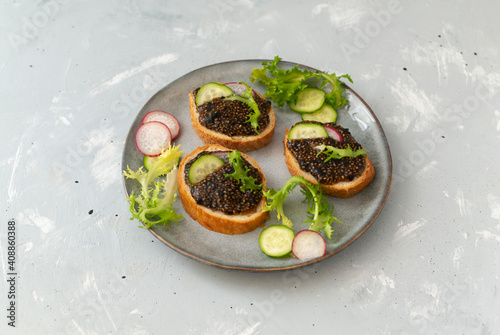 Chia seeds, soy sauce and wakame snack on baguette pieces on a gray plate on a gray background. Copy space. Horizontal orientation.