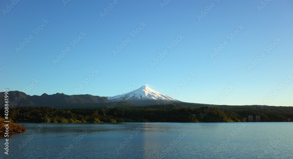 Nature of Chile, Beautiful panoramic landscape, lake Villarrica and snow capped Villarrica volcano under blue sky evning light. Pucon