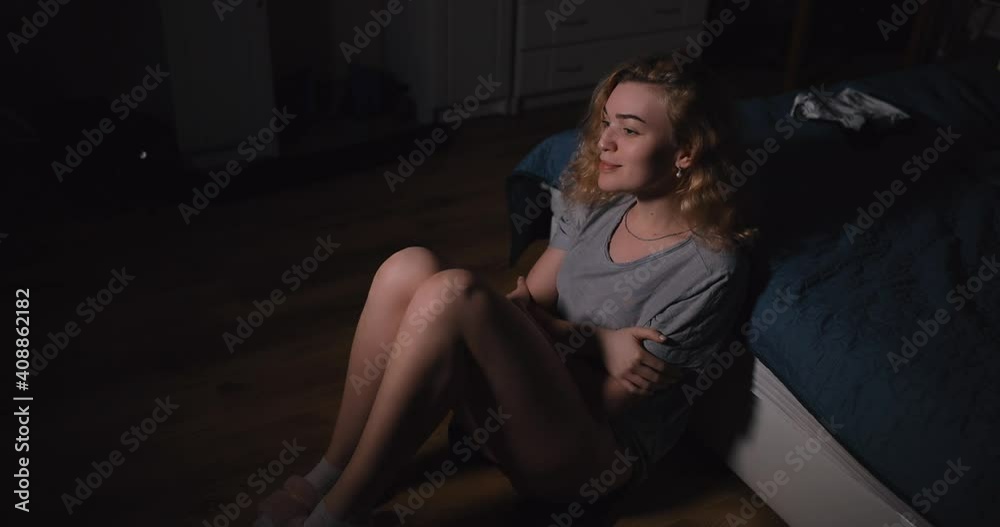 Sexy woman with naked legs sitting on a floor near bed at home