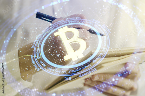 Double exposure of creative Bitcoin symbol hologram with man hand writing in notepad on background. Mining and blockchain concept