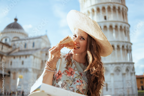smiling young solo traveller woman in floral dress with pizza