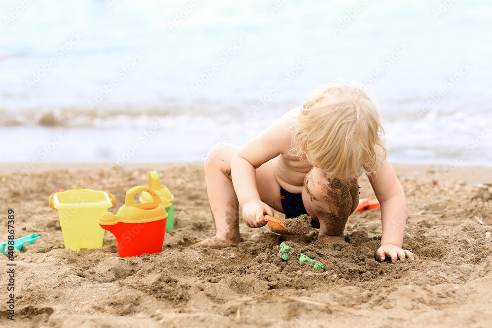 Little boy playing on the beach with plastic toys. Summertime, vacation, travel, childhood concept. Little boy playing on the beach with plastic toys. Summertime, vacation, travel, childhood concept.