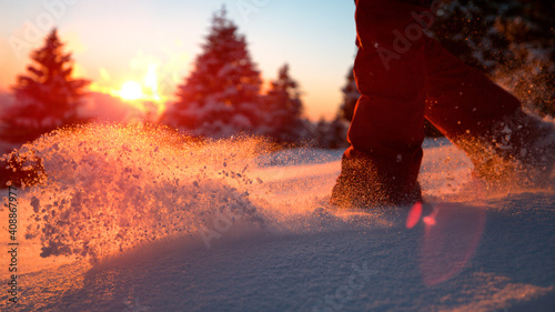CLOSE UP: Unrecognizable female tourist treads the deep powder snow at sunrise. © helivideo