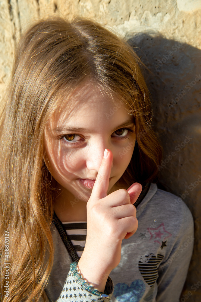 Naklejka premium girl teenager puts her finger to her nose, as if keeping something secret