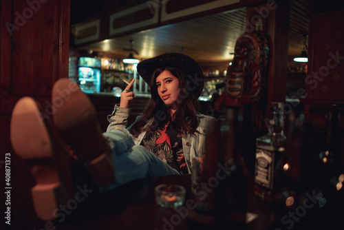 Cowgirl woman smoking and drinking in a bar