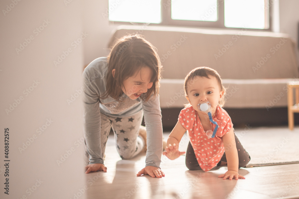 Girl play with her little sister at home. They have fun when walk on all fours Girl play with her little sister at home. They have fun when walk on all fours