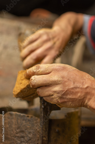 Sculptor's hand stained with clay preparing molding machine. Shallow depth of field
