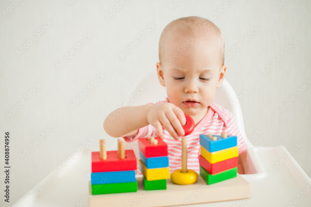 little girl plays with an educational toy - a multi-colored wooden pyramid. Development of fine motor skills and logical thinking. High quality photo little girl plays with an educational toy - a multi-colored wooden pyramid. Development of fine motor skills and logical thinking. High quality photo