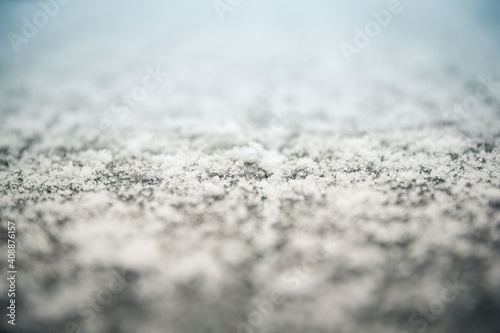 Close up of winter nature background of fluffy white snow. Abstract contrast of fresh snow melting on wet wooden deck plank surface. Soft focus