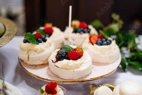 Mini Pavlova meringue cake with fresh berries on a pink and golden plate