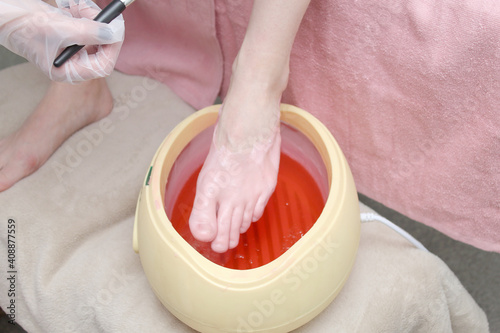 Fototapeta woman foot treatment in paraffin bath at the spa.