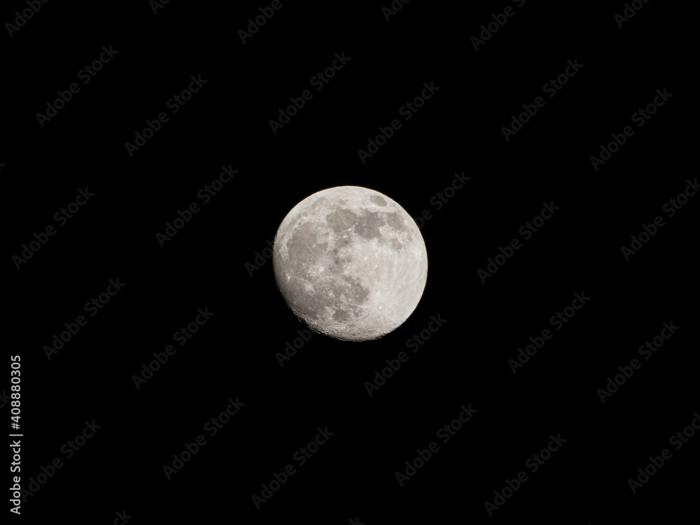 closeup of a nearly full moon with its craters in the black night sky closeup of a nearly full moon with its craters in the black night sky