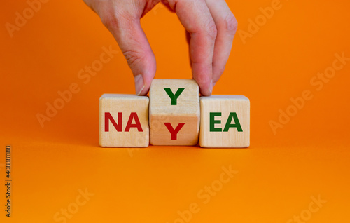 Yea or nay symbol. Businessman turns a cube, changes the word 'nay' to 'yea'. Beautiful orange background. Copy space. Business, motivation and yea or nay concept. photo