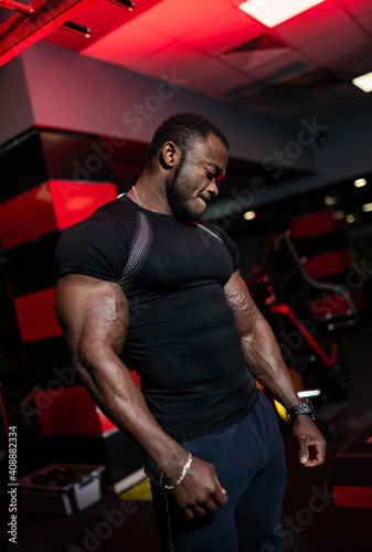 Afro american sports man looking at side over dark background. Perfect muscular body with strong muscles.