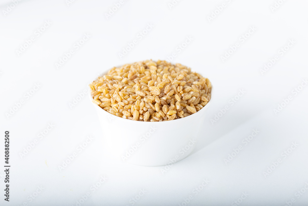 Uncooked bulgur wheat in white ceramic bowl isolated on white background. Uncooked bulgur wheat in white ceramic bowl isolated on white background.
