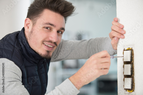 side view of young man repairing light switch at home © auremar