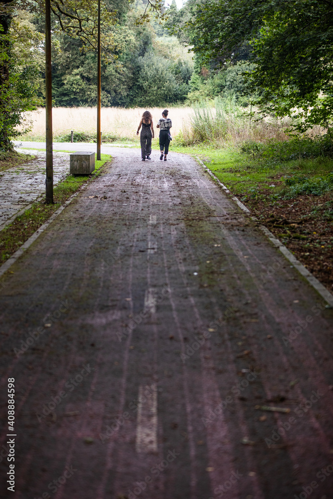 Obraz premium Two women walking along the bike path in a town in Galicia. In front they have a cornfield
