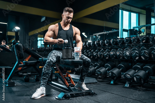 athlete man preparing protein cocktail or use sport nutrition supplement in gym photo
