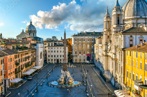 Fototapeta Naklejka Na Ścianę i Meble -  View from a window overlooking the Piazza Navona early morning, showing the cathedral, sidewalk cafes, tourists and the fountain of the Four Rivers.