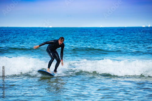 Man learns to surf on the surfboard getting used to standing on the board on small waves