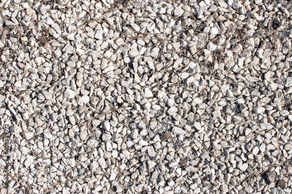 A texture of many little grey white stones laying on ground A texture of many little grey white stones laying on ground