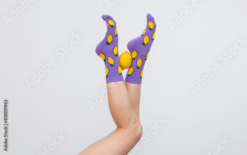 female legs in colorful socks with lemons isolated on white background