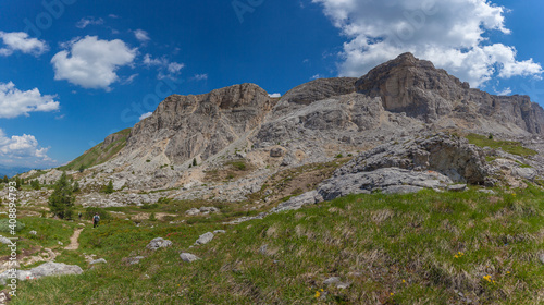 Panorama of Mount Settsass western side with unrecognizable man walking on a hiking trail, Dolomites, Italy