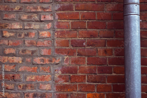 antique red brick wall with metallic water pipe - city background  place for text message and announcement