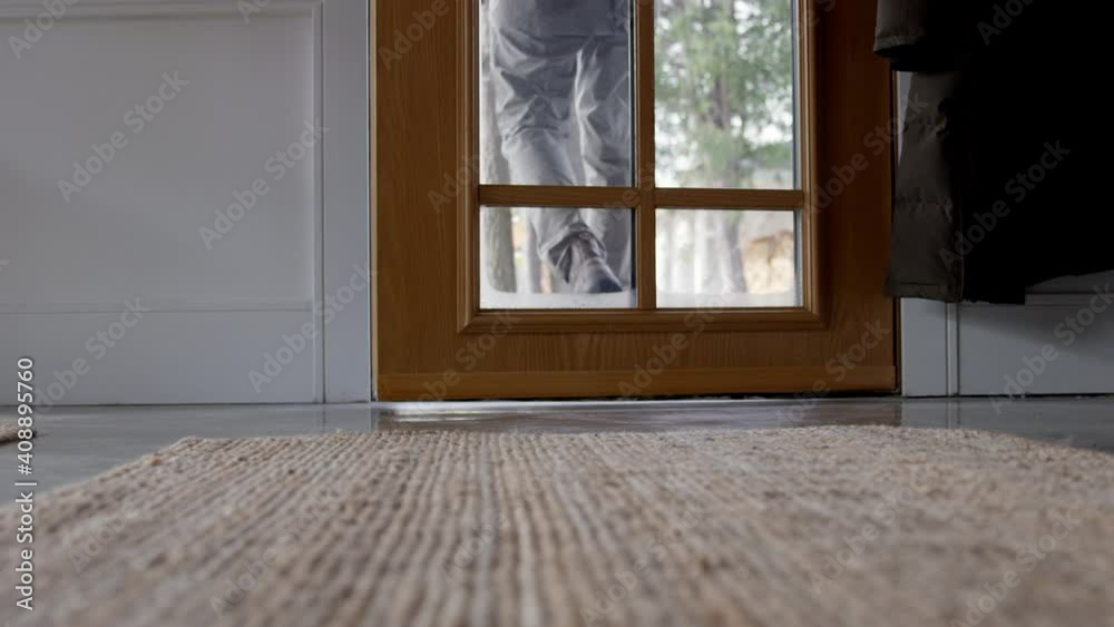 Man closes front door behind himself in winter - close up on feet