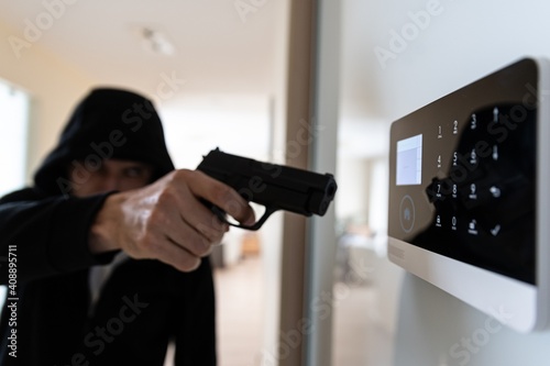 A thief with a gun breaks into the apartment. There is an alarm on the wall to disarm.