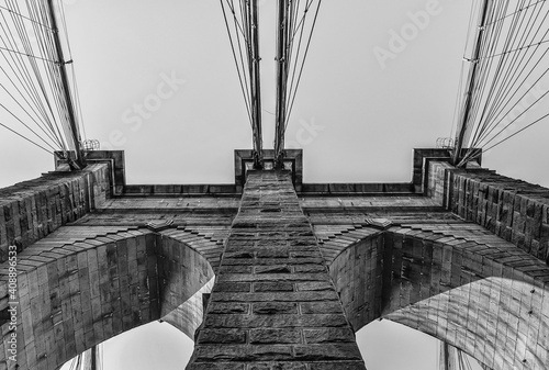 Close up view from below of Brooklyn Bridge - a hybrid cable-stayed/suspension bridge in New York City, spanning the East River between the boroughs of Manhattan and Brooklyn. Black and white photo.