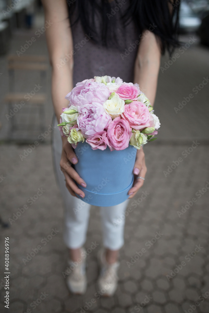A brunette girl with long black hair holds a large round box with pastel colors in her hands. A brunette girl with long black hair holds a large round box with pastel colors in her hands.
