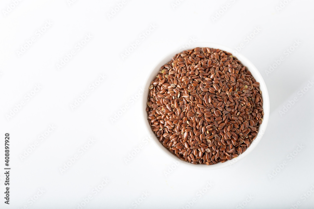 Flax seeds in white bowl on white background. Flax seeds in white bowl on white background.